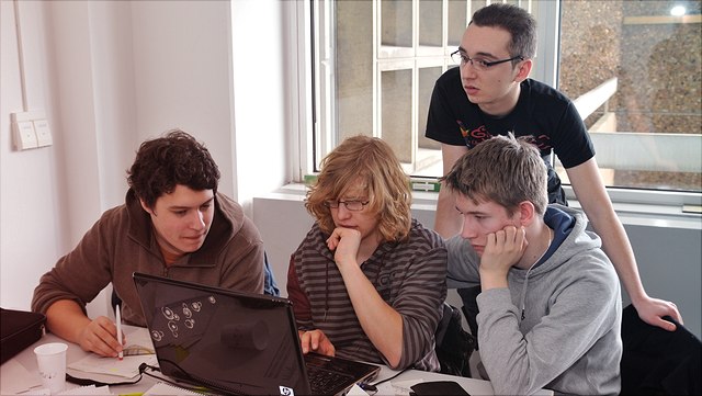 Vier Lernende gucken auf einen Laptop